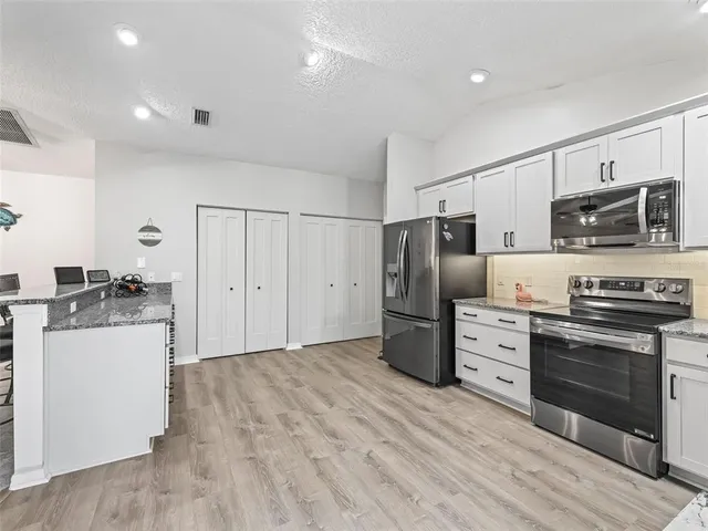 a view of a kitchen with white cabinets and wooden floor