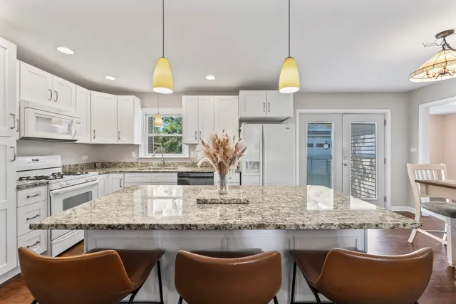 a kitchen with stainless steel appliances granite countertop a sink a stove a dining table and chairs