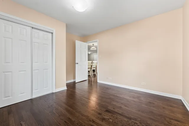 a view of an empty room with wooden floor and closet