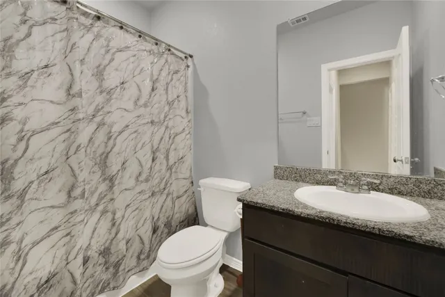 a bathroom with a granite countertop sink toilet and a mirror