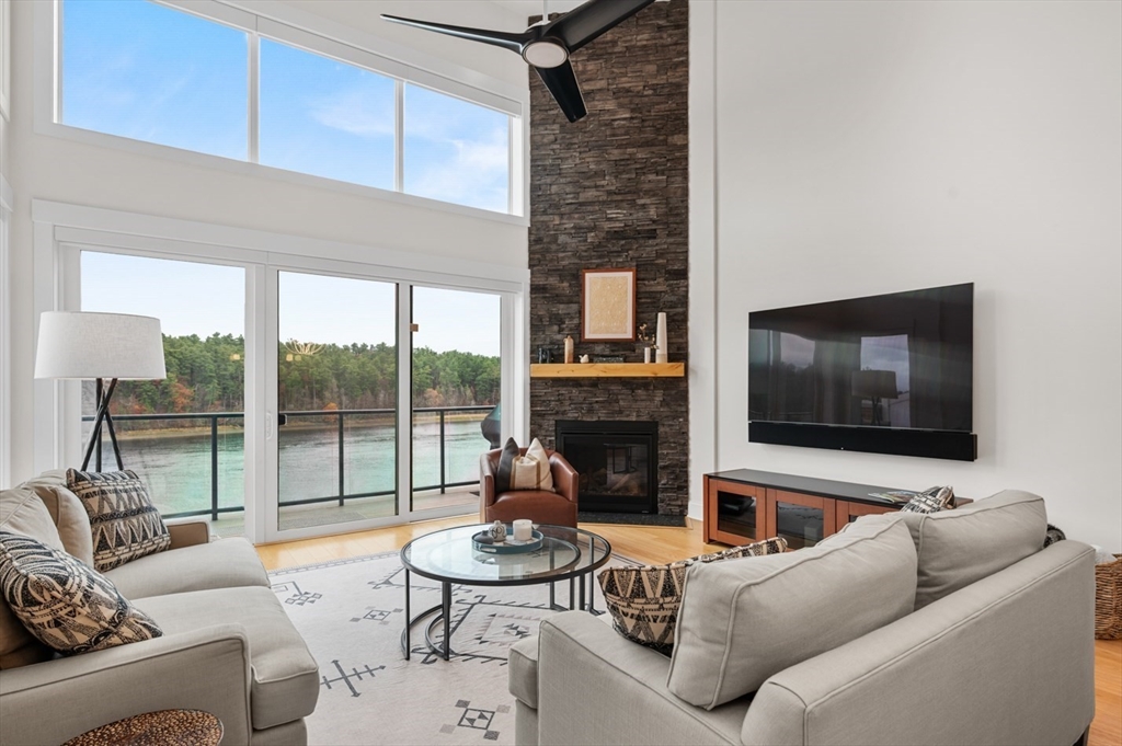 60 Merrimac Street, Unit 504 Amesbury, MA 01913 - Photo 8 of 37 a living room with furniture a floor to ceiling window and a flat screen tv