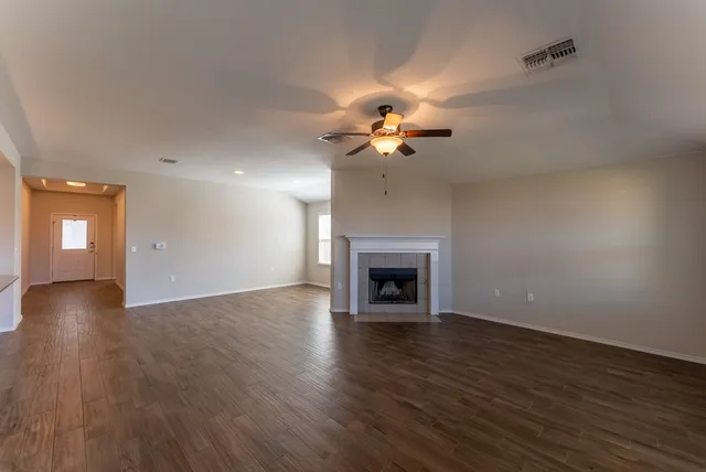 a view of an empty room with wooden floor and a fireplace