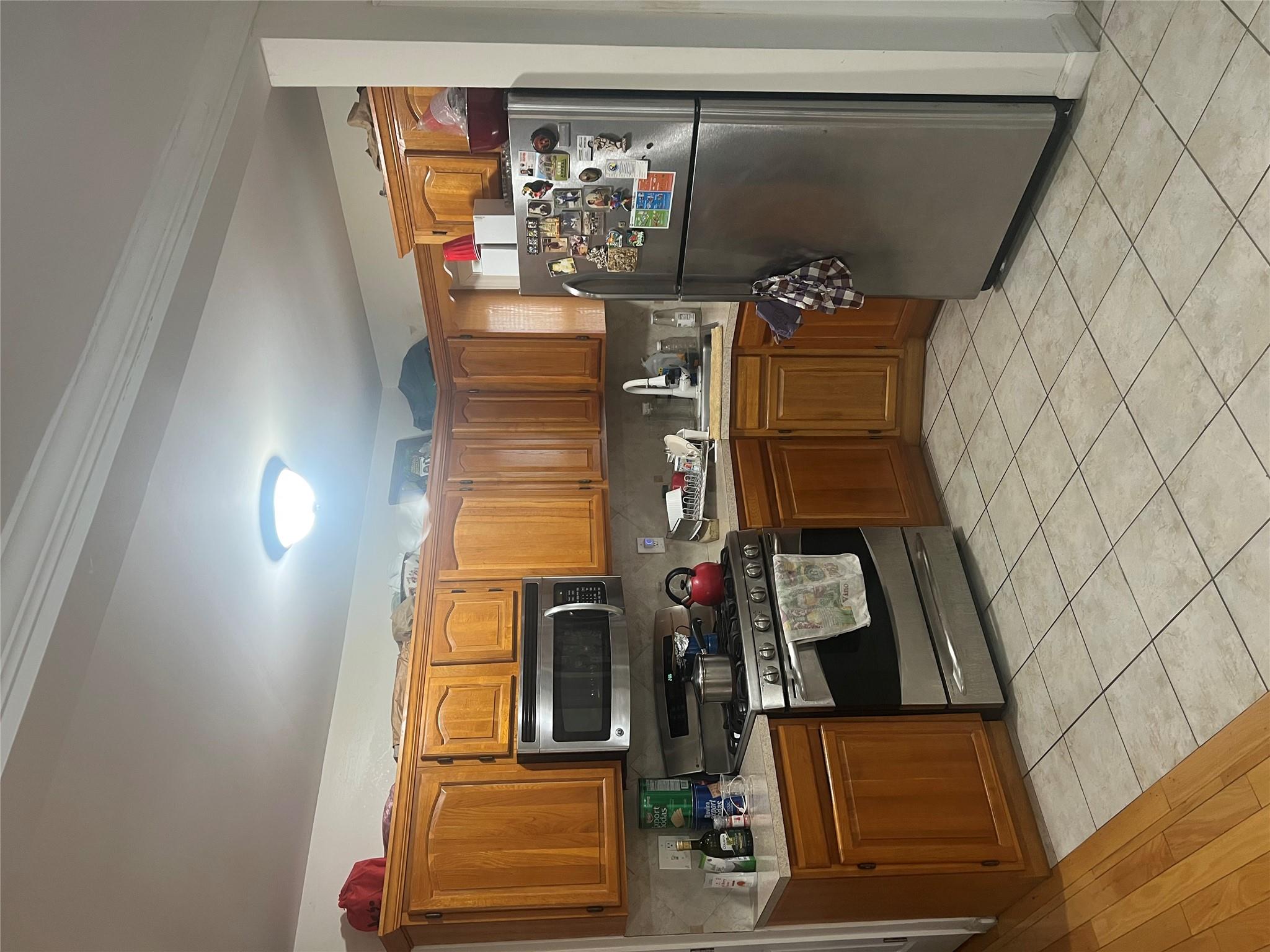 303 Beach 84th Street Queens, NY 11693 - Photo 6 of 16 Kitchen with brown cabinetry, refrigerator, light countertops, and range