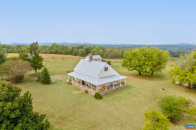 a white house with a big yard and large trees