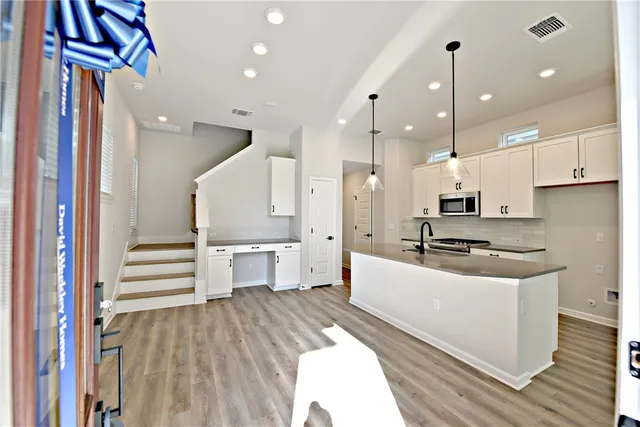 a large white kitchen with a stove a sink dishwasher and a refrigerator with wooden floor