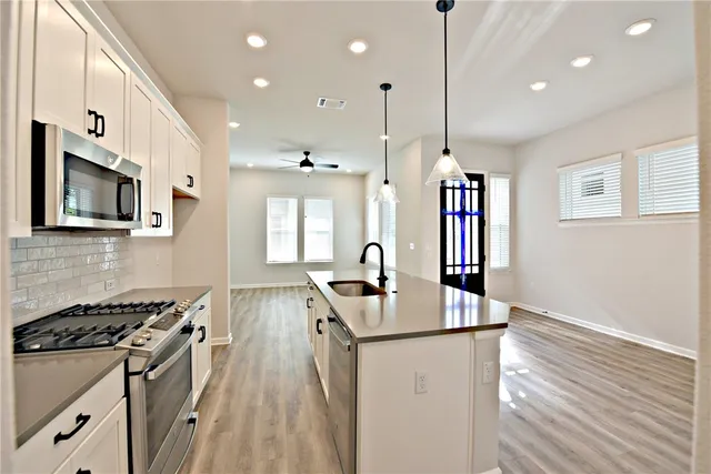 a kitchen with stainless steel appliances granite countertop a sink stove and wooden floor
