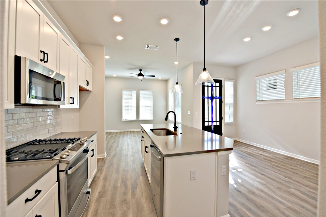13602 Defiance Pass Austin, TX 78717 - Photo 4 of 19 a kitchen with stainless steel appliances granite countertop a sink stove and wooden floor