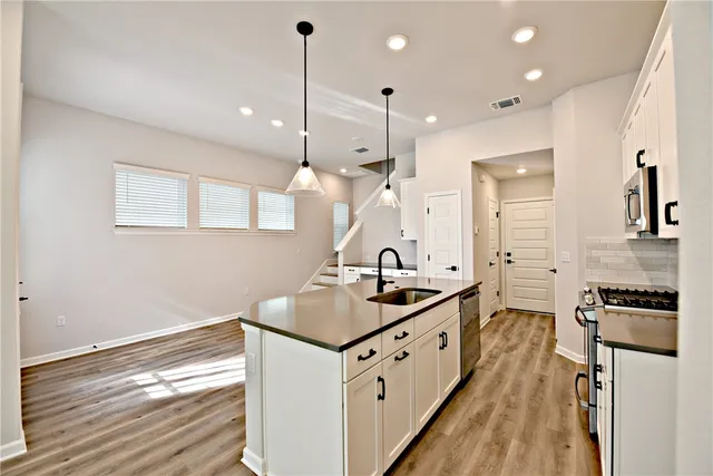a kitchen with granite countertop a sink a counter space appliances and cabinets