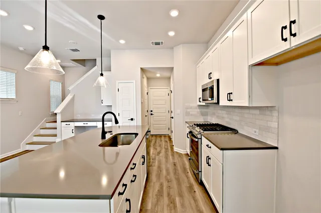 a kitchen with kitchen island a sink appliances and cabinets
