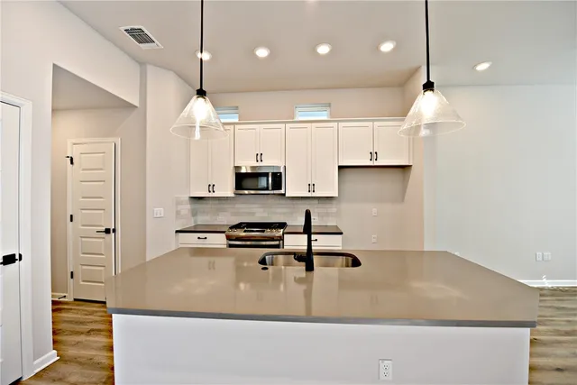 a kitchen with stainless steel appliances granite countertop a sink a stove and a refrigerator