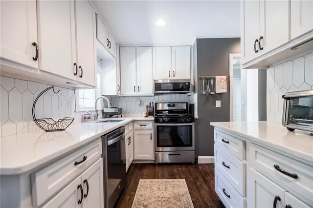 a kitchen with cabinets stainless steel appliances a sink and wooden floor