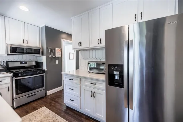 a kitchen with stainless steel appliances a refrigerator a stove and white cabinets