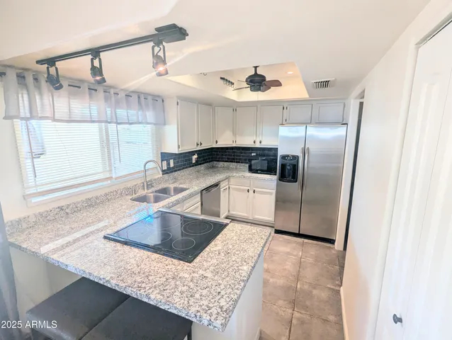 a kitchen with stainless steel appliances granite countertop a sink a stove a refrigerator and cabinets