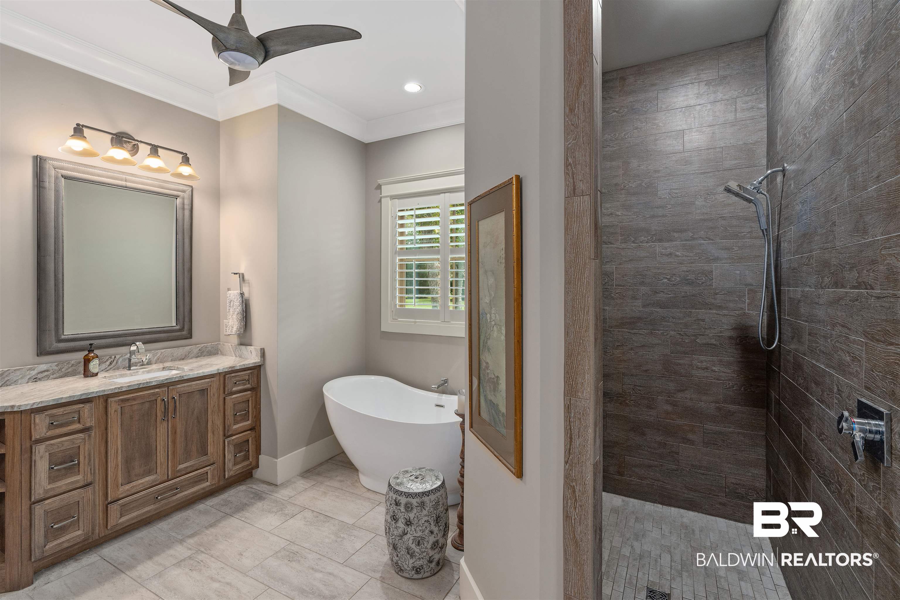 8753 Bishop Road Fairhope, AL 36532 - Photo 29 of 59 Bathroom featuring a freestanding soaking tub, a single vanity with a stone countertop, a framed mirror, and a walk-in shower with large format tile walls and a mosaic tile floor