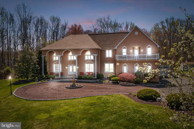 a front view of a house with yard and trees in the background