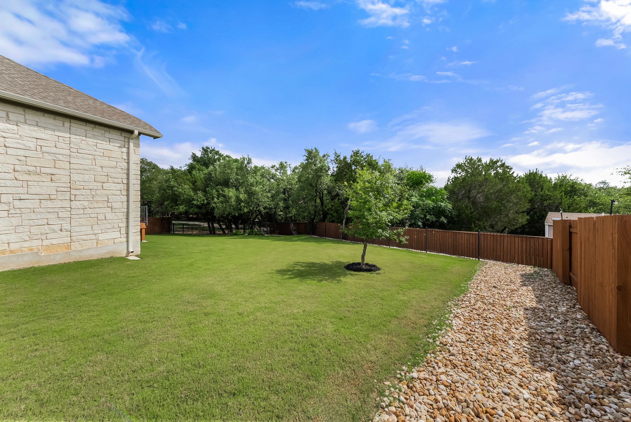 300 Prato Place Georgetown, TX 78628 - Photo 37 of 40 A spacious, verdant yard invites outdoor activities, bordered by natural landscaping and a charming stone path.