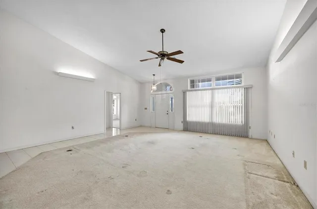 an empty room with a ceiling fan and window