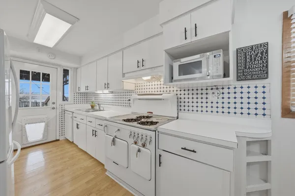 a kitchen with granite countertop white cabinets and white appliances