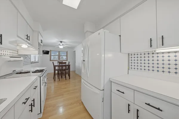 a kitchen with granite countertop a sink a stove a refrigerator and white cabinets