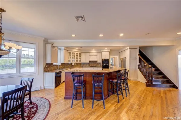 a dining area with stainless steel appliances granite countertop a table and chairs with wooden floor