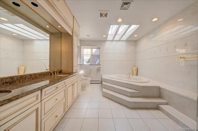 a large white bathroom with a granite countertop sink and a mirror