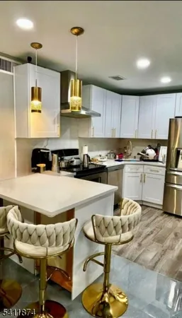 a kitchen with stainless steel appliances granite countertop a sink a stove a refrigerator and chairs