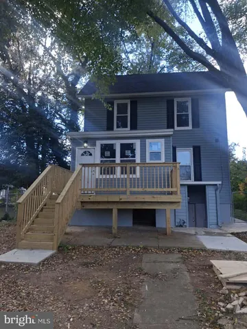 a backyard of a house with wooden deck and outdoor seating