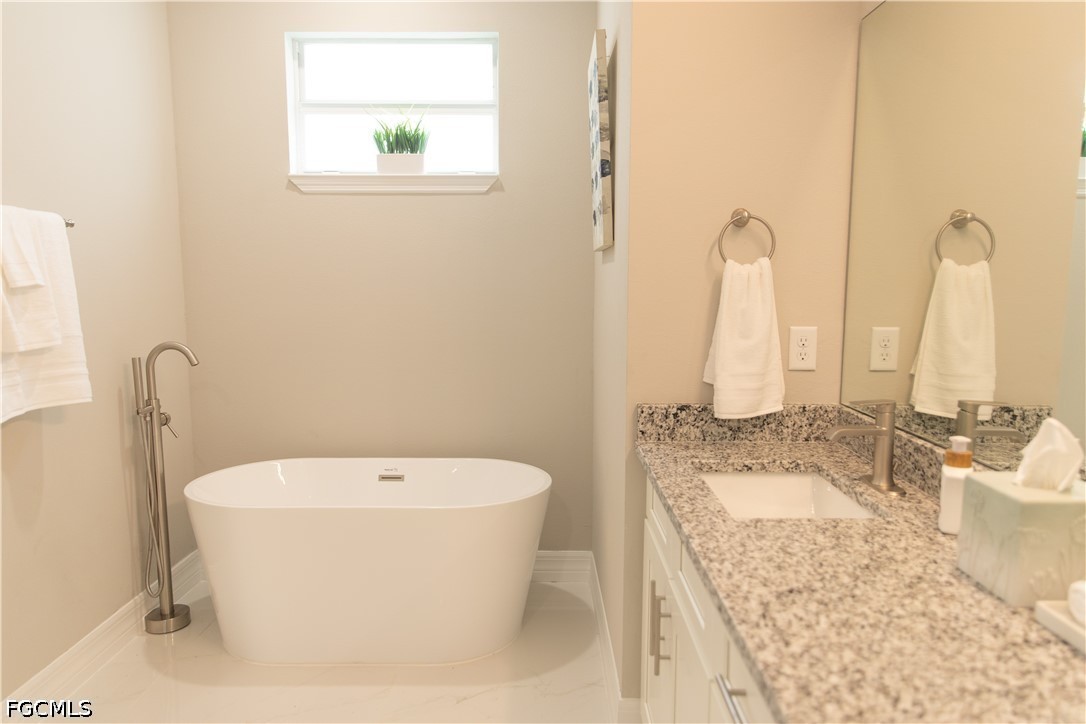 1228 Chrisholm Street Lehigh Acres, FL 33974 - Photo 12 of 18 a bathroom with a granite countertop sink a toilet and bathtub