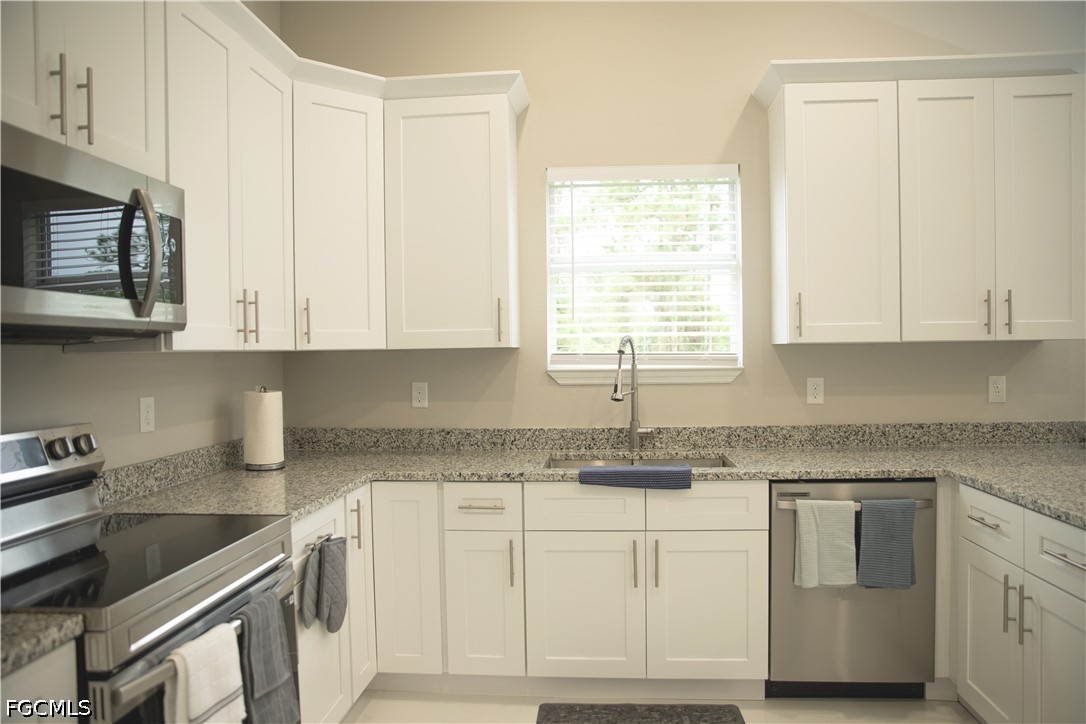 1228 Chrisholm Street Lehigh Acres, FL 33974 - Photo 5 of 18 a kitchen with granite countertop white cabinets and white appliances