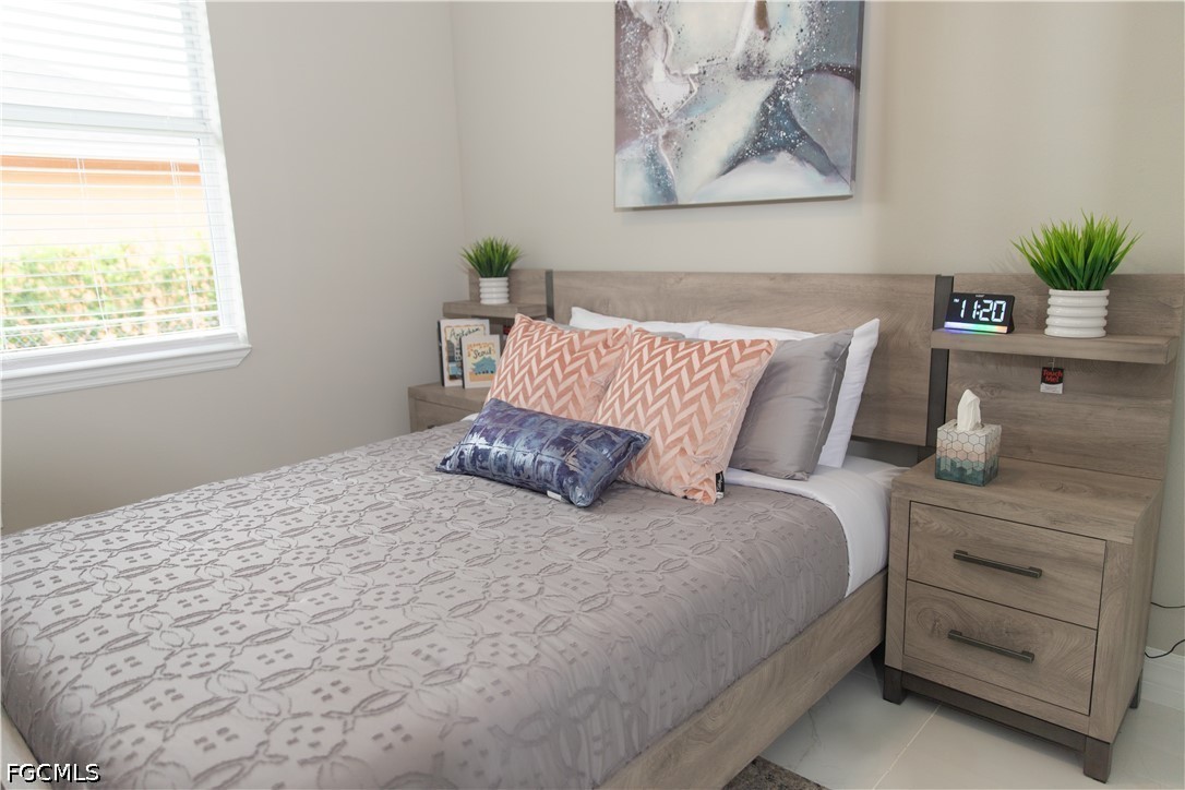 1228 Chrisholm Street Lehigh Acres, FL 33974 - Photo 9 of 18 a large bed sitting in a bedroom next to a window with potted plant