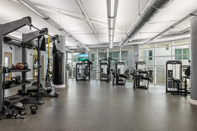a view of a room with gym equipment and wooden floor