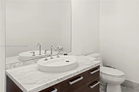 a bathroom with a granite countertop sink and a toilet