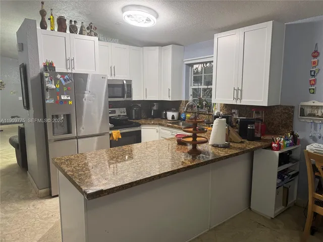 a kitchen with granite countertop a sink a counter top space and cabinets