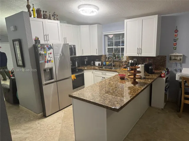 a kitchen with stainless steel appliances granite countertop a refrigerator a stove a sink and a refrigerator