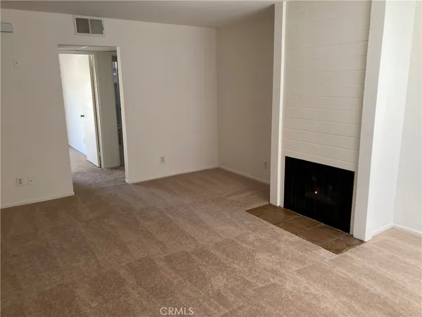 an empty room with windows and fireplace