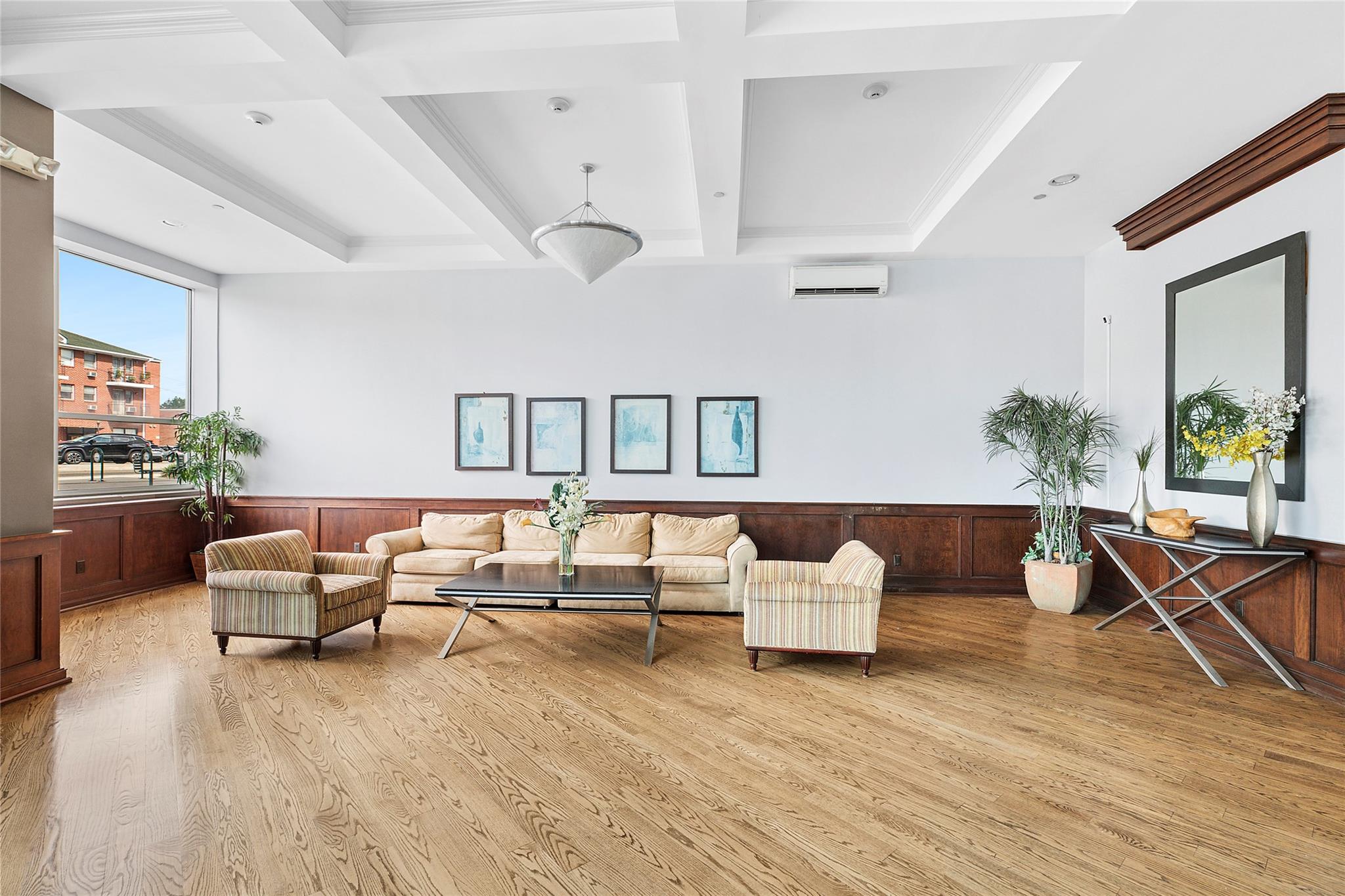 130 Post Avenue, Unit 316 Westbury, NY 11590 - Photo 14 of 15 Living area featuring light wood-type flooring, coffered ceiling, beam ceiling, and a wainscoted wall