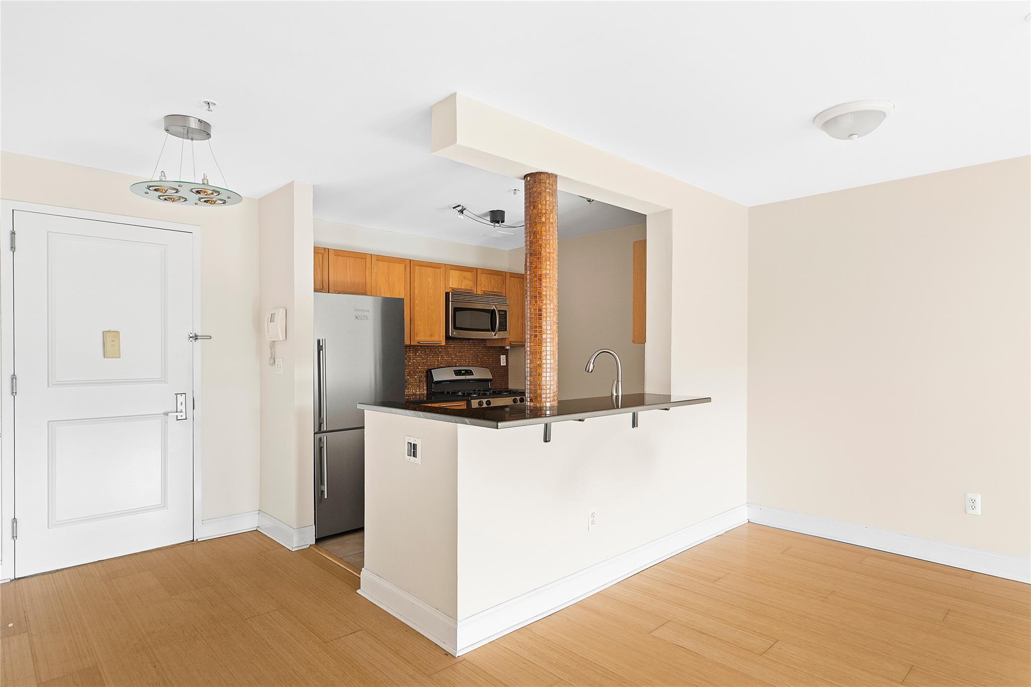 130 Post Avenue, Unit 316 Westbury, NY 11590 - Photo 3 of 15 Kitchen with appliances with stainless steel finishes, a peninsula, dark countertops, a kitchen breakfast bar, and decorative backsplash