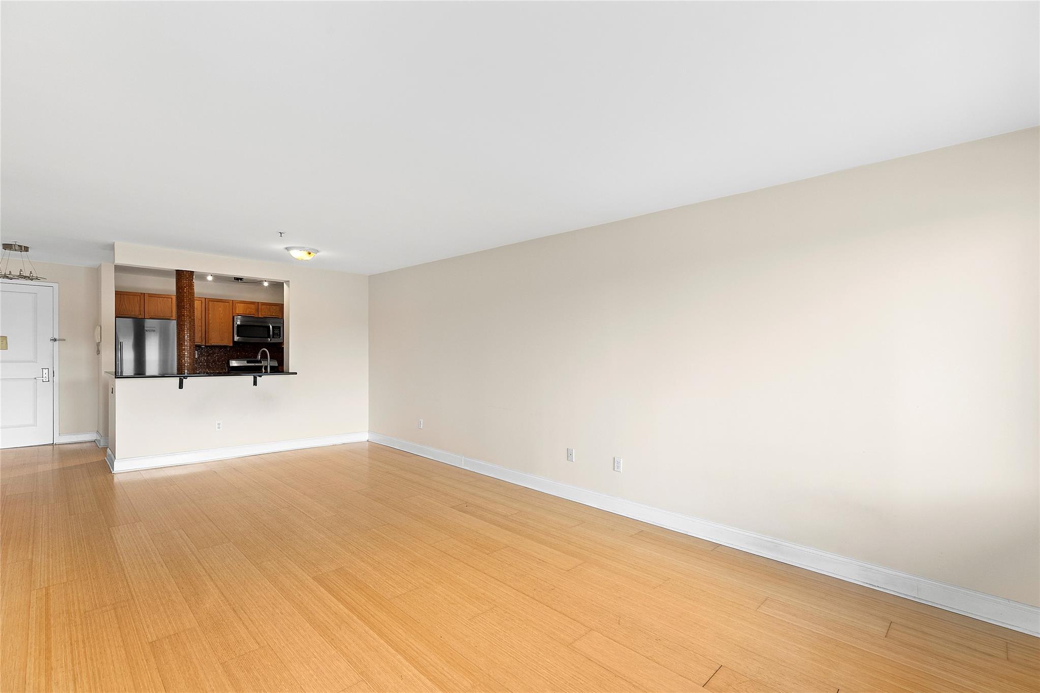 130 Post Avenue, Unit 316 Westbury, NY 11590 - Photo 6 of 15 Unfurnished living room with baseboards and light wood finished floors