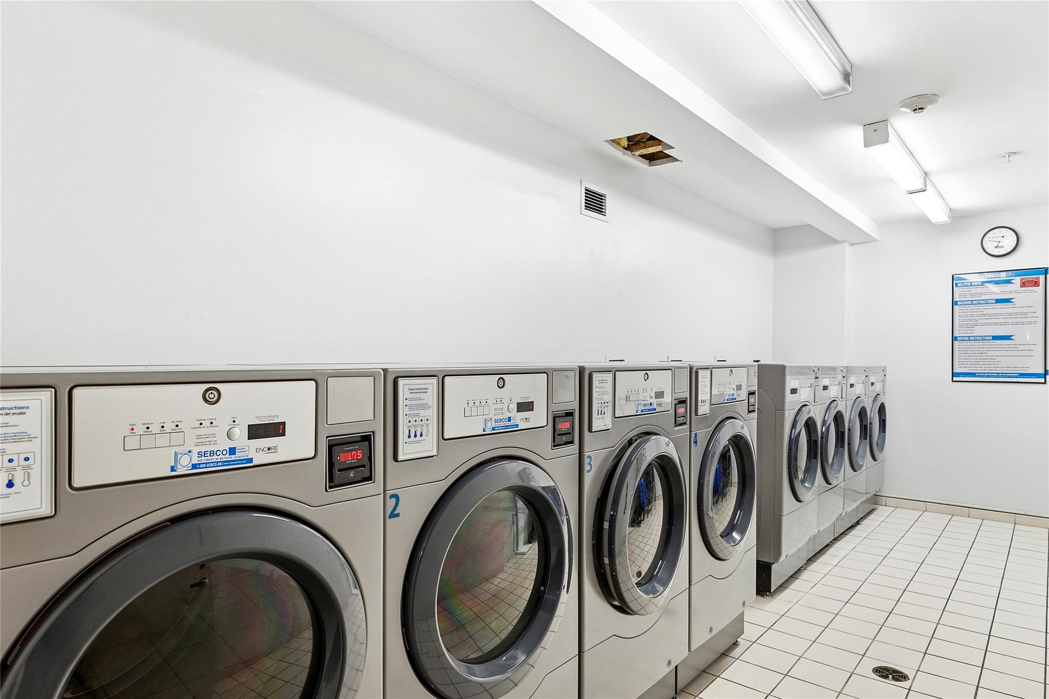 130 Post Avenue, Unit 316 Westbury, NY 11590 - Photo 10 of 15 Shared laundry room with washer and clothes dryer and light tile patterned floors