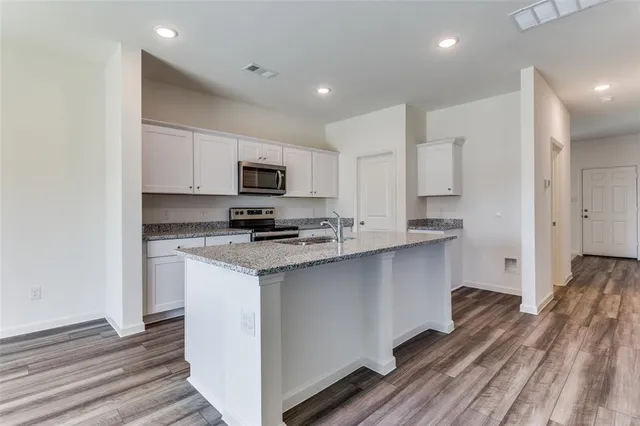 a kitchen with stainless steel appliances granite countertop a sink stove and refrigerator