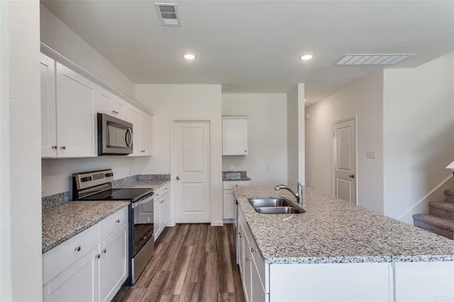 a kitchen with granite countertop a sink stove and refrigerator