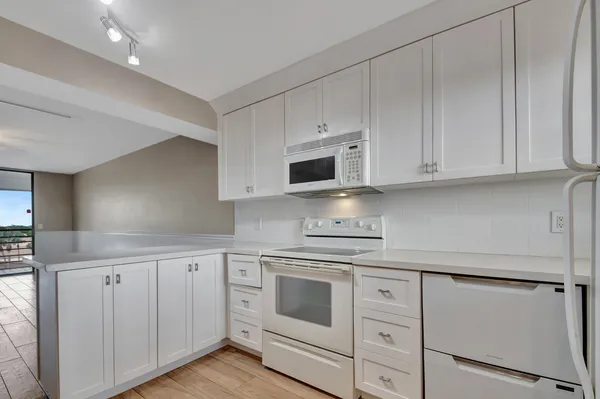 a kitchen with white cabinets and white appliances
