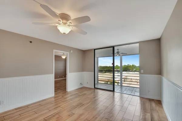 an empty room with wooden floor fan and windows