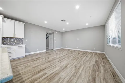 a view of an empty room with a window and wooden floor