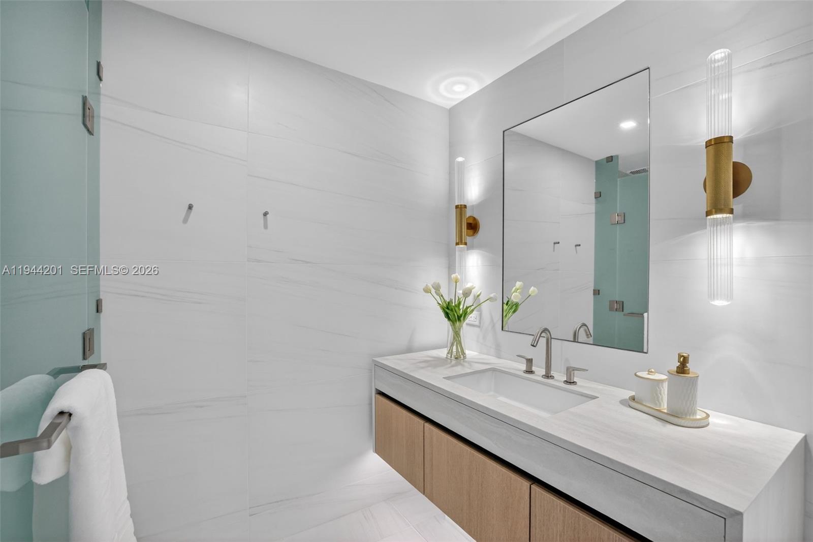 900 North Ocean Boulevard, Unit 906 Pompano Beach, FL 33062 - Photo 35 of 100 The 06 line primary bath feels like a private spa. Oversized and beautifully proportioned, it features a frameless glass walk in shower, designer soaking tub, dual vanities with stone counters, and sleek modern fixtures. Clean architectural lines, neutral luxury finishes, and generous storage for a calm, resort style retreat that complements the open coastal aesthetic of the residence.