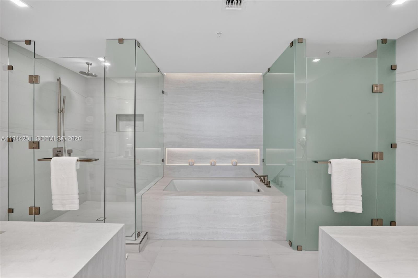 900 North Ocean Boulevard, Unit 906 Pompano Beach, FL 33062 - Photo 35 of 100 The 06 line primary bath feels like a private spa. Oversized and beautifully proportioned, it features a frameless glass walk in shower, designer soaking tub, dual vanities with stone counters, and sleek modern fixtures. Clean architectural lines, neutral luxury finishes, and generous storage for a calm, resort style retreat that complements the open coastal aesthetic of the residence.