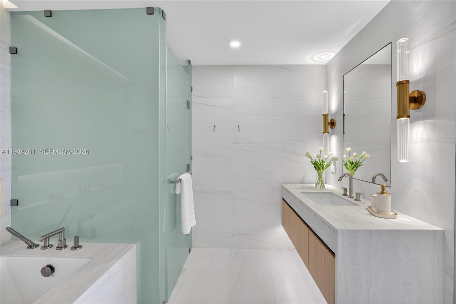900 North Ocean Boulevard, Unit 906 Pompano Beach, FL 33062 - Photo 37 of 100 The 06 line primary bath feels like a private spa. Oversized and beautifully proportioned, it features a frameless glass walk in shower, designer soaking tub, dual vanities with stone counters, and sleek modern fixtures. Clean architectural lines, neutral luxury finishes, and generous storage for a calm, resort style retreat that complements the open coastal aesthetic of the residence.