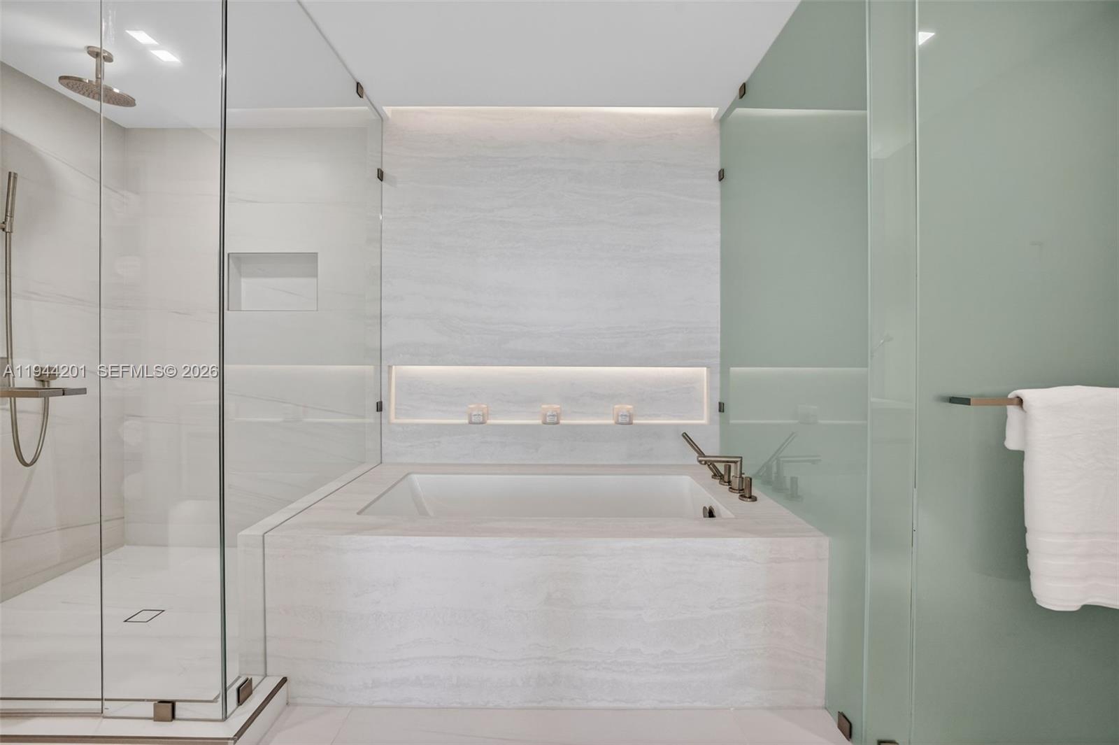 900 North Ocean Boulevard, Unit 906 Pompano Beach, FL 33062 - Photo 38 of 100 The 06 line primary bath feels like a private spa. Oversized and beautifully proportioned, it features a frameless glass walk in shower, designer soaking tub, dual vanities with stone counters, and sleek modern fixtures. Clean architectural lines, neutral luxury finishes, and generous storage for a calm, resort style retreat that complements the open coastal aesthetic of the residence.