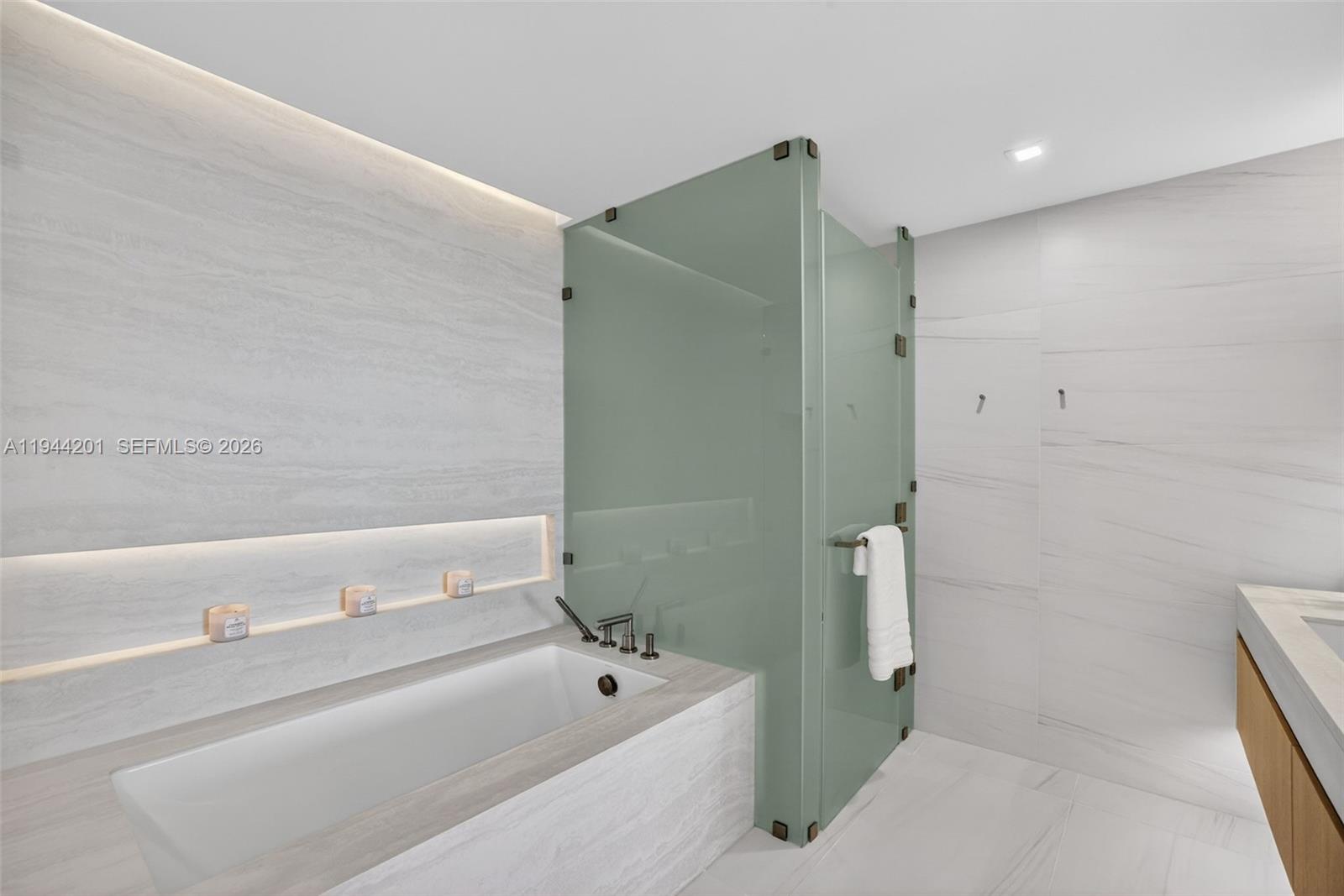 900 North Ocean Boulevard, Unit 906 Pompano Beach, FL 33062 - Photo 39 of 100 The 06 line primary bath feels like a private spa. Oversized and beautifully proportioned, it features a frameless glass walk in shower, designer soaking tub, dual vanities with stone counters, and sleek modern fixtures. Clean architectural lines, neutral luxury finishes, and generous storage for a calm, resort style retreat that complements the open coastal aesthetic of the residence.