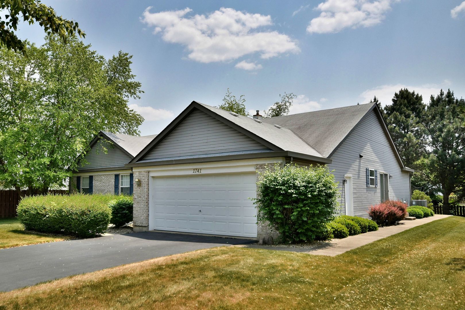 a view of a house with a small yard plants and a large tree